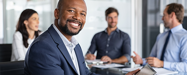 Four smiling people around a desk during a meeting